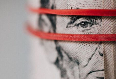 Investment Glossary - Closeup of rolled United States five dollar bills tightened with red rubber band