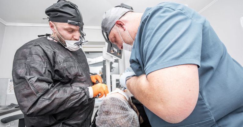 Patient Capital - Two men in surgical masks and gloves are working on a patient