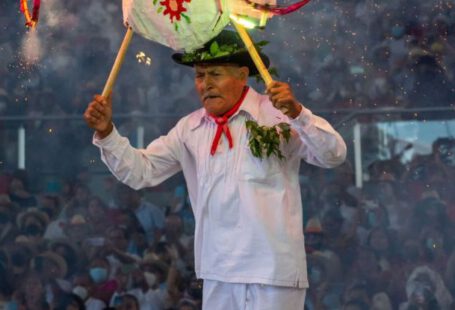 Early Stage - A man in white holding a firework on his head