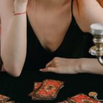 Future Prediction - A Woman in Black Tank Top Holding a Tarot Card while Covering Her One Eye