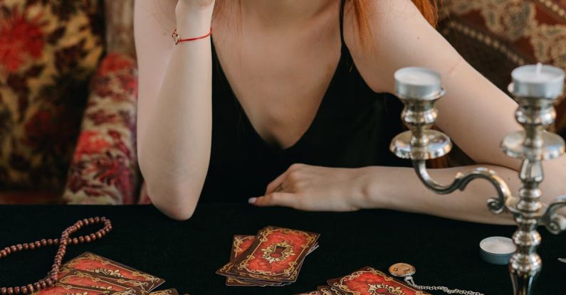 Future Prediction - A Woman in Black Tank Top Holding a Tarot Card while Covering Her One Eye