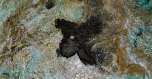 Economic Waves - A small black rock in the middle of the ocean