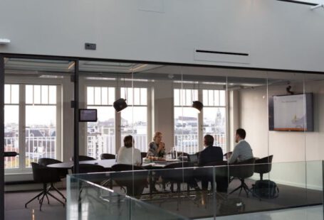 Syndicate Meeting - A large glass walled office with people sitting at tables