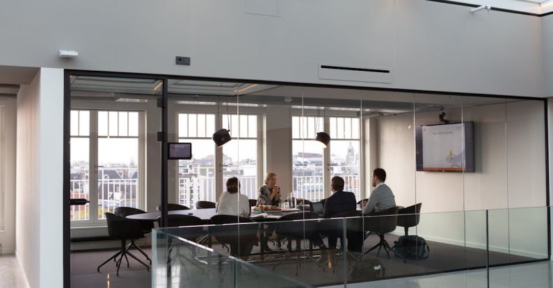 Syndicate Meeting - A large glass walled office with people sitting at tables